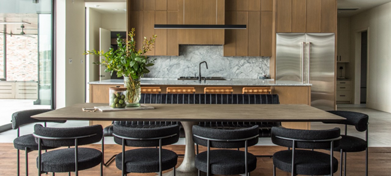 Modern kitchen and dining area with retro and industrial design elements, featuring a wooden dining table, black chairs, and a marble backsplash. 