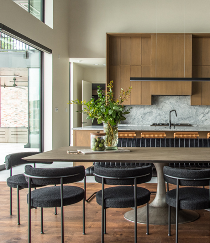 Modern kitchen and dining area with retro and industrial design elements, featuring a wooden dining table, black chairs, and a marble backsplash. 