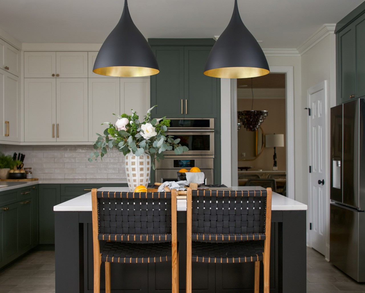 Modern kitchen with a central island painted Caviar by Sherwin-Williams, pendant lights, Pewter Green and Greek Villa cabinets, Drift of Mist walls, and a vase with flowers.