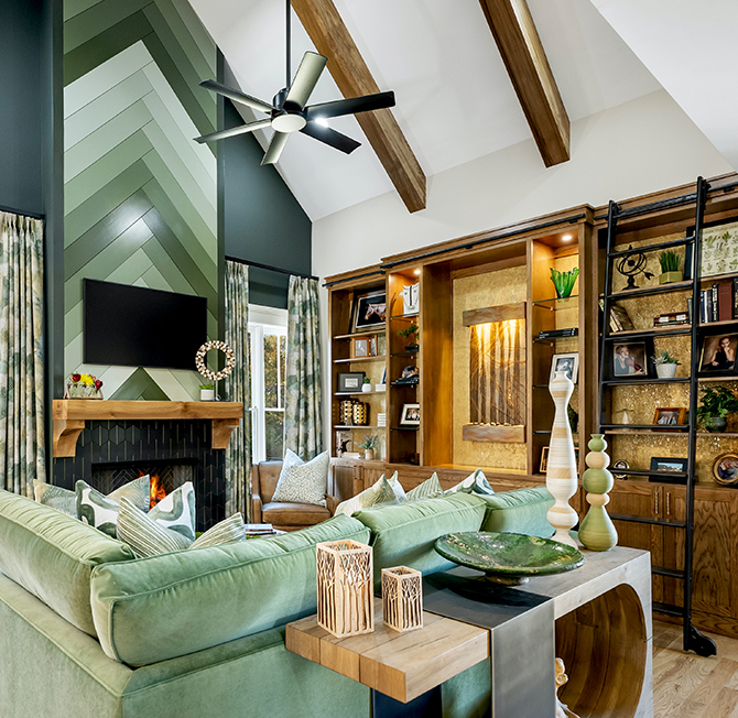 A modern living room with a green-accented fireplace, green sectional sofa, wooden shelves, and vaulted ceiling with wooden beams.