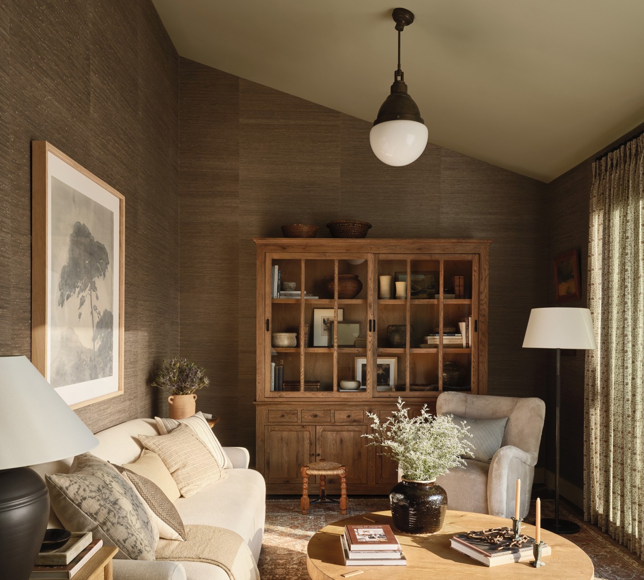 Cozy living room with beige sofa and wooden furniture, featuring earth-toned decor and soft lighting.