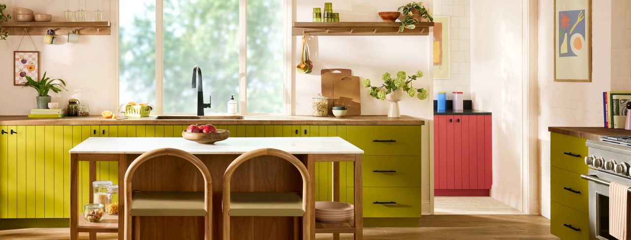 A modern kitchen with Offbeat Green cabinets, a central island, and a large window.