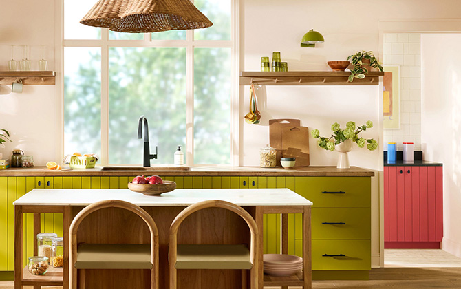 A modern kitchen with Offbeat Green cabinets, a central island, and a large window.