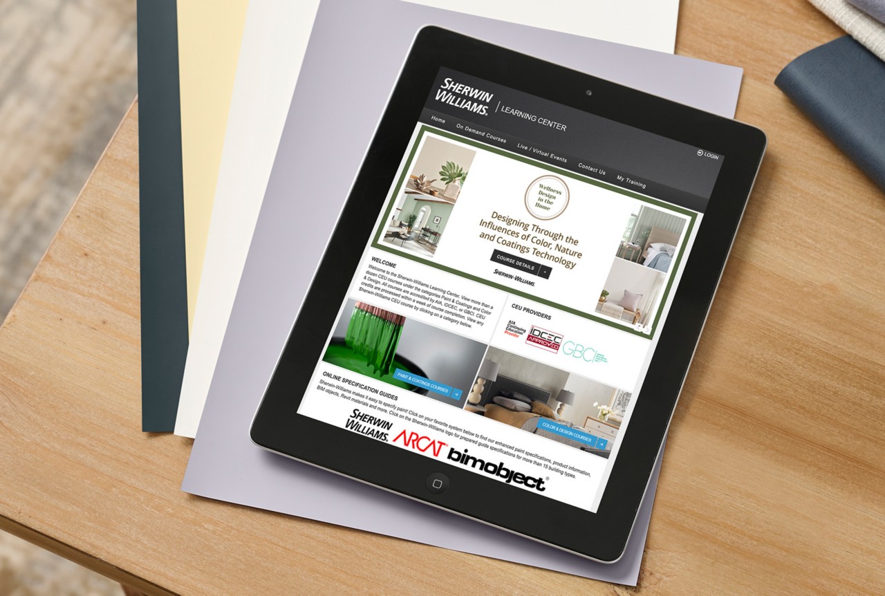 Electronic tablet on top of large-sized color samples on a wooden desktop with the Design Education Center webpage featured on screen.