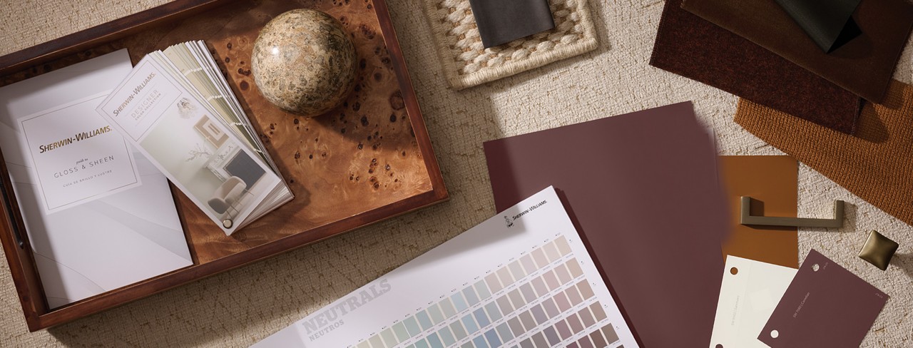 Flatlay of various Sherwin-Williams designer color tools, materials, and samples arrayed on a surface.
