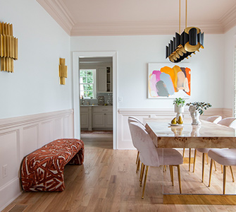 A dining room with light wood floors and white walls and a wooden dining room table with chairs with a pink hue material.