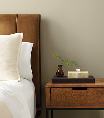 A bedroom with a bed and nightstand with walls painted in SW 9517 Outrigger.