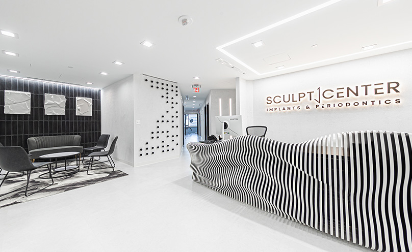 Lobby or reception area of Sculpt Center Implants and Periodontics with white and black color scheme and sculptural, undulating front desk.