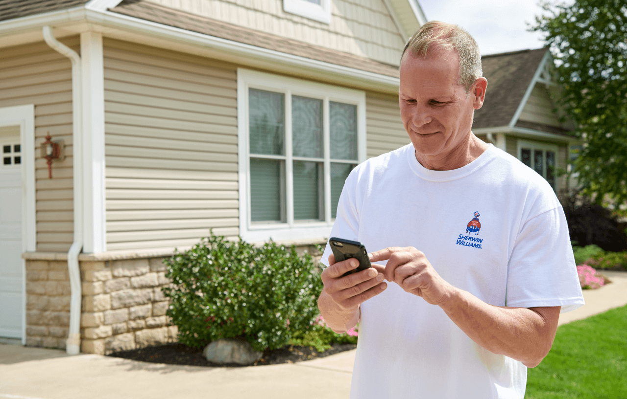 A painting contractor using the Sherwin-Williams PRO+ App on his smart phone.