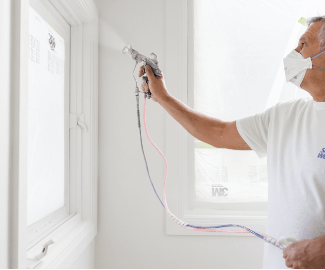 A person applying paint with a sprayer.