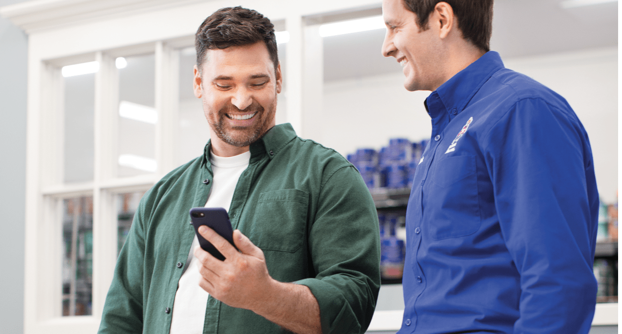 A painter and Sherwin-Williams employee looking at a phone.