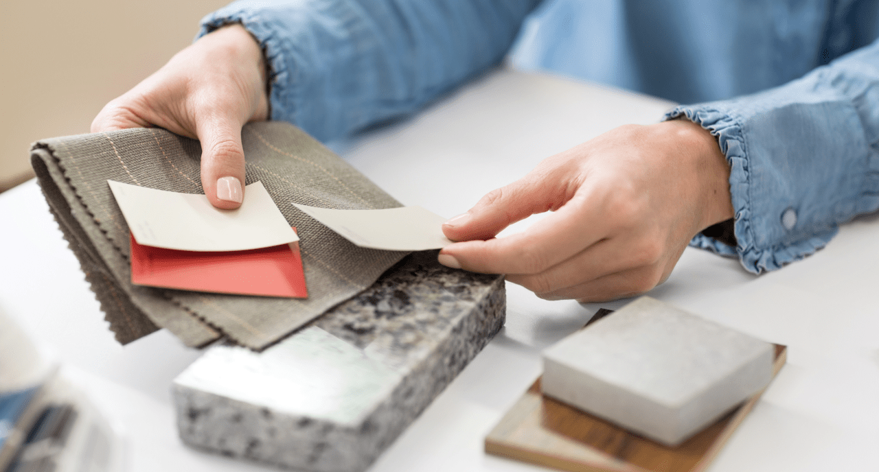 A person comparing paint, textile and stone swatches.