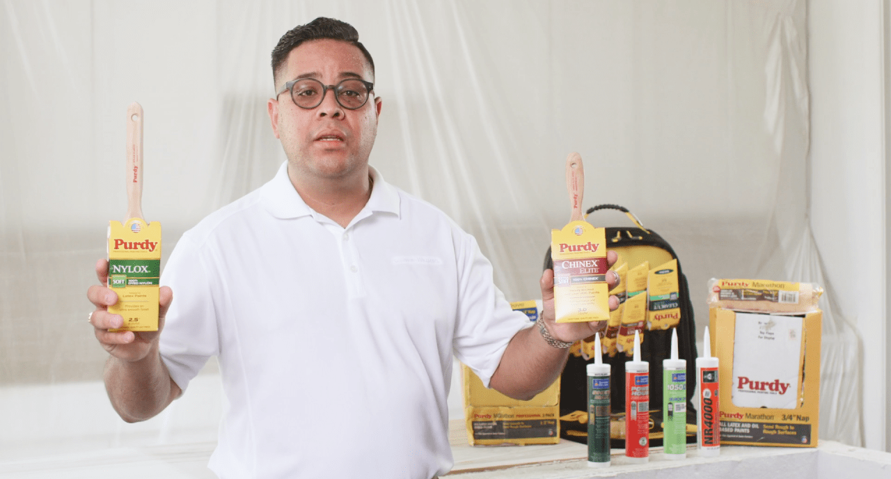 A person holding two Purdy brushes.