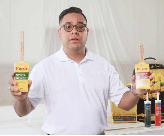 A person holding two Purdy brushes.