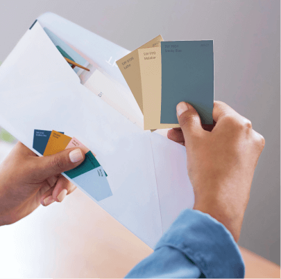 A person pulling three different color chips out of an envelope.