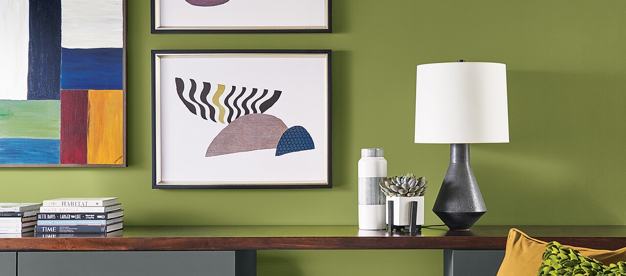 A bright green painted wall with abstract paintings and decor.