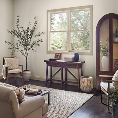 A living room with walls painted Pure White SW 7005 and a brown leather chair and a wood and metal side table in front of a white trimmed window.