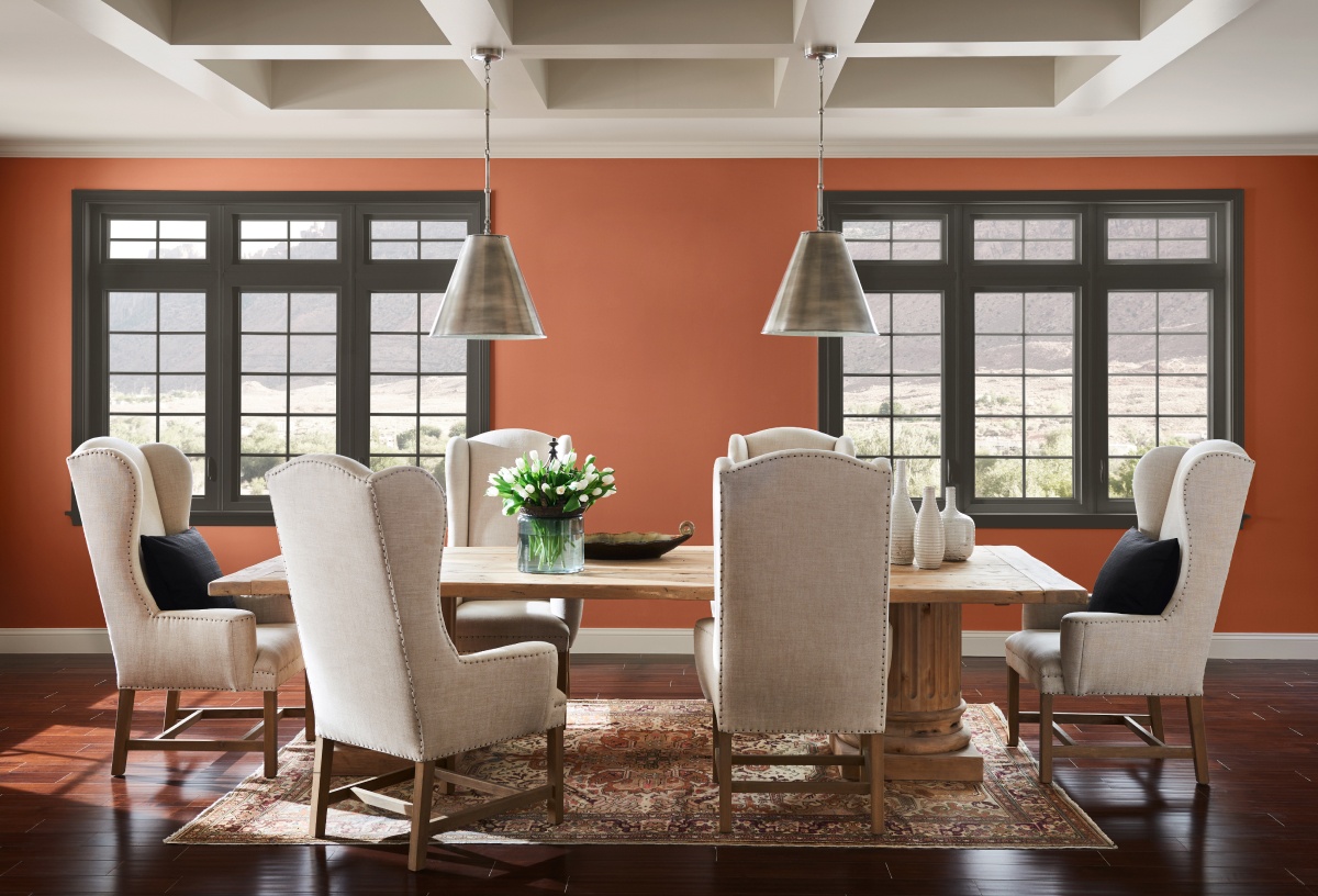 A traditional dining room with vibrant orange wall and pendant chandelier