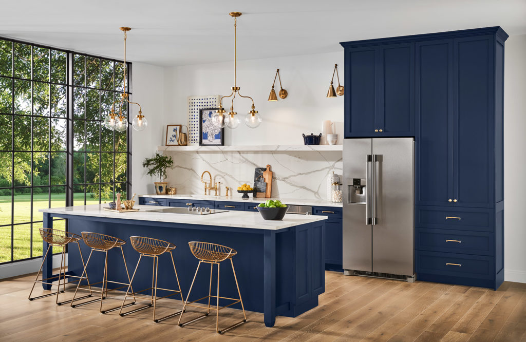 Kitchen with Sherwin Williams 2020 Color of the Year Naval SW 6244 painted cabinets and island, white marble backsplash, and gold accents. 