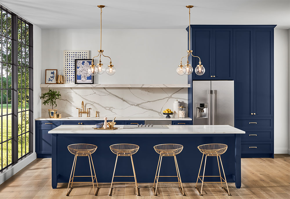 Kitchen with Sherwin Williams 2020 Color of the Year Naval SW 6244 painted cabinets and island, white marble backsplash, and gold accents. 