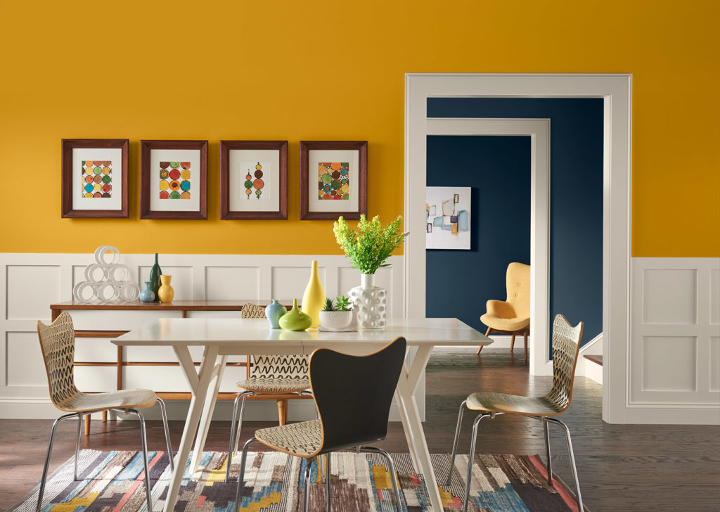 Modern dining room with yellow and white walls, a white wooden table and green floral center piece. 