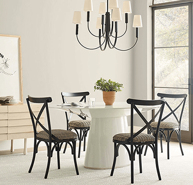 A high end dining room with white walls, white table, and black accent chairs