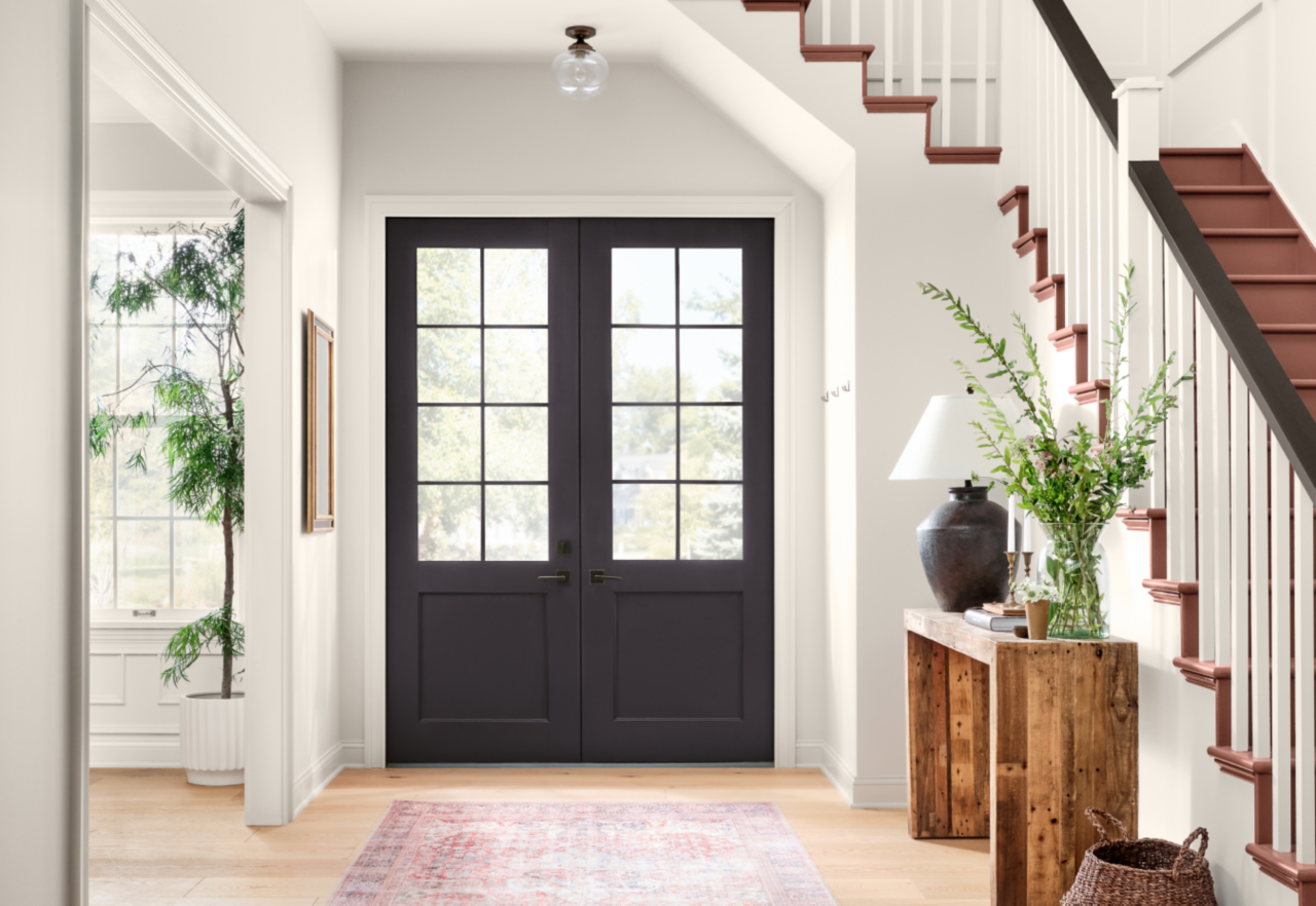 An entryway with dark brown french doors, stairs, and side table