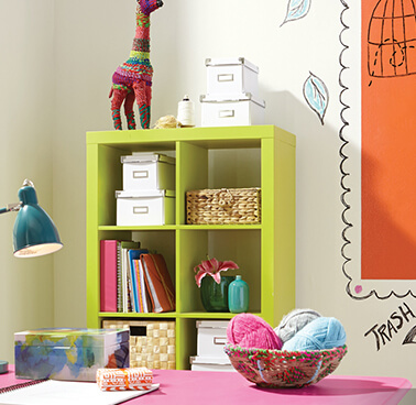 A colorful kids desk space with green shelves and a pink desk .