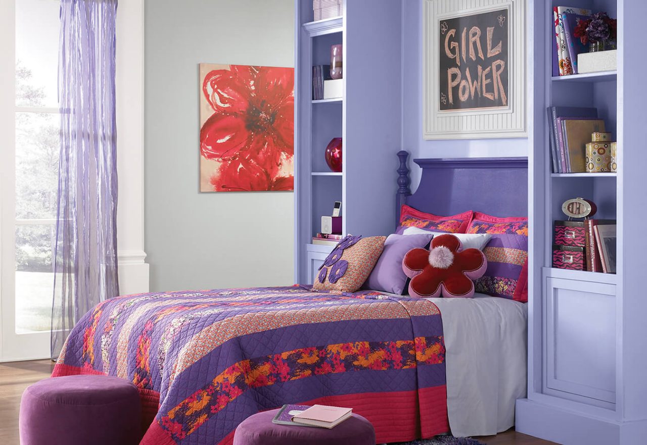 A girls bedroom with pink and purple bedding.