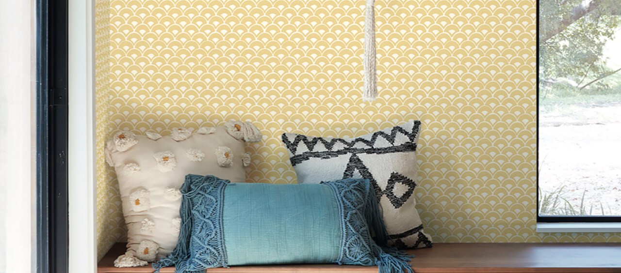 An entryway with bench and pillows and a yellow fan design wallpaper wall