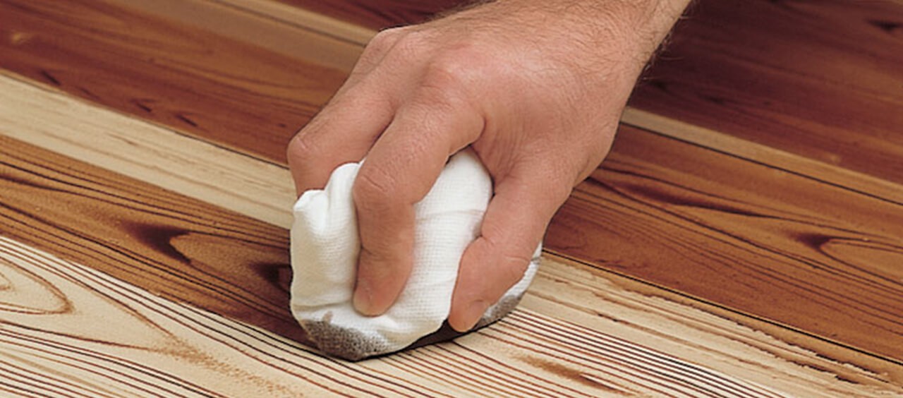 A closeup of a hand staining a raw piece of wood