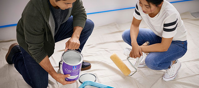 Two people painting a bedroom with white paint