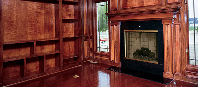 A wood stained living room with a fireplace.