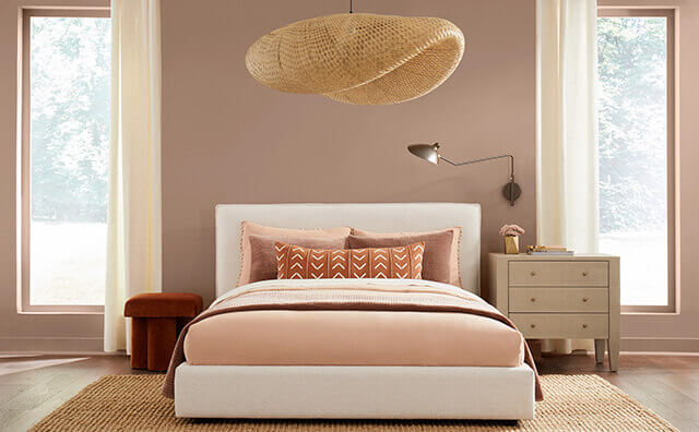 A nude painted bedroom with pink sheets and accented decor. 